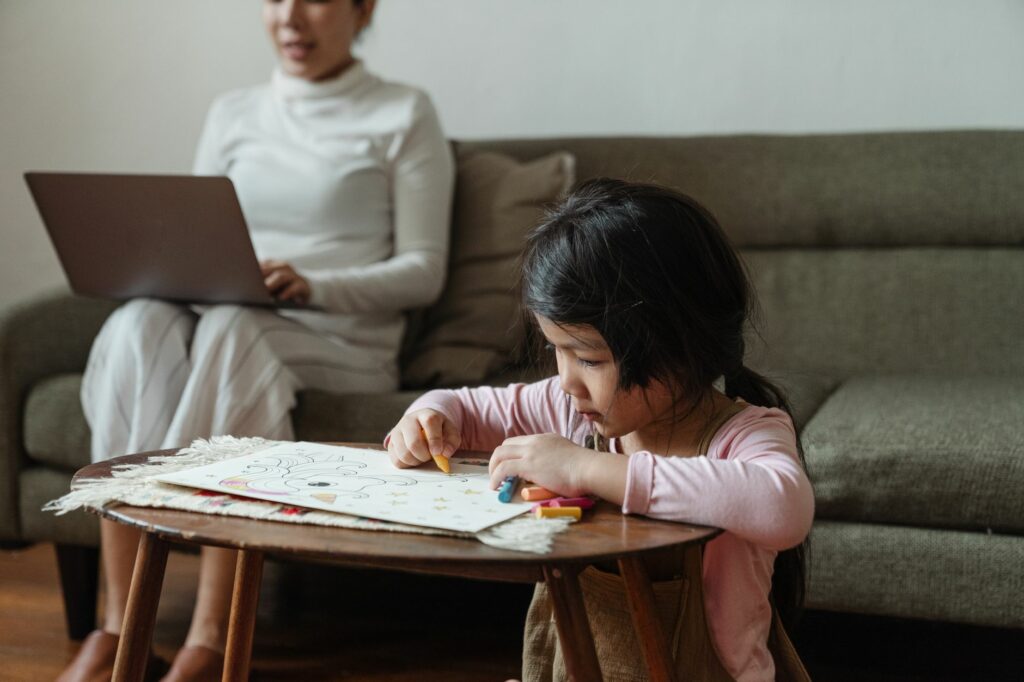 Mamma che lavora da casa con il laptop mentre il figlio gioca accanto a lei